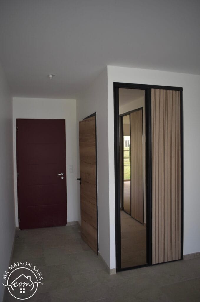 entrée vue de l'intérieur, placard encastré, porte d'entrée rouge et porte bois